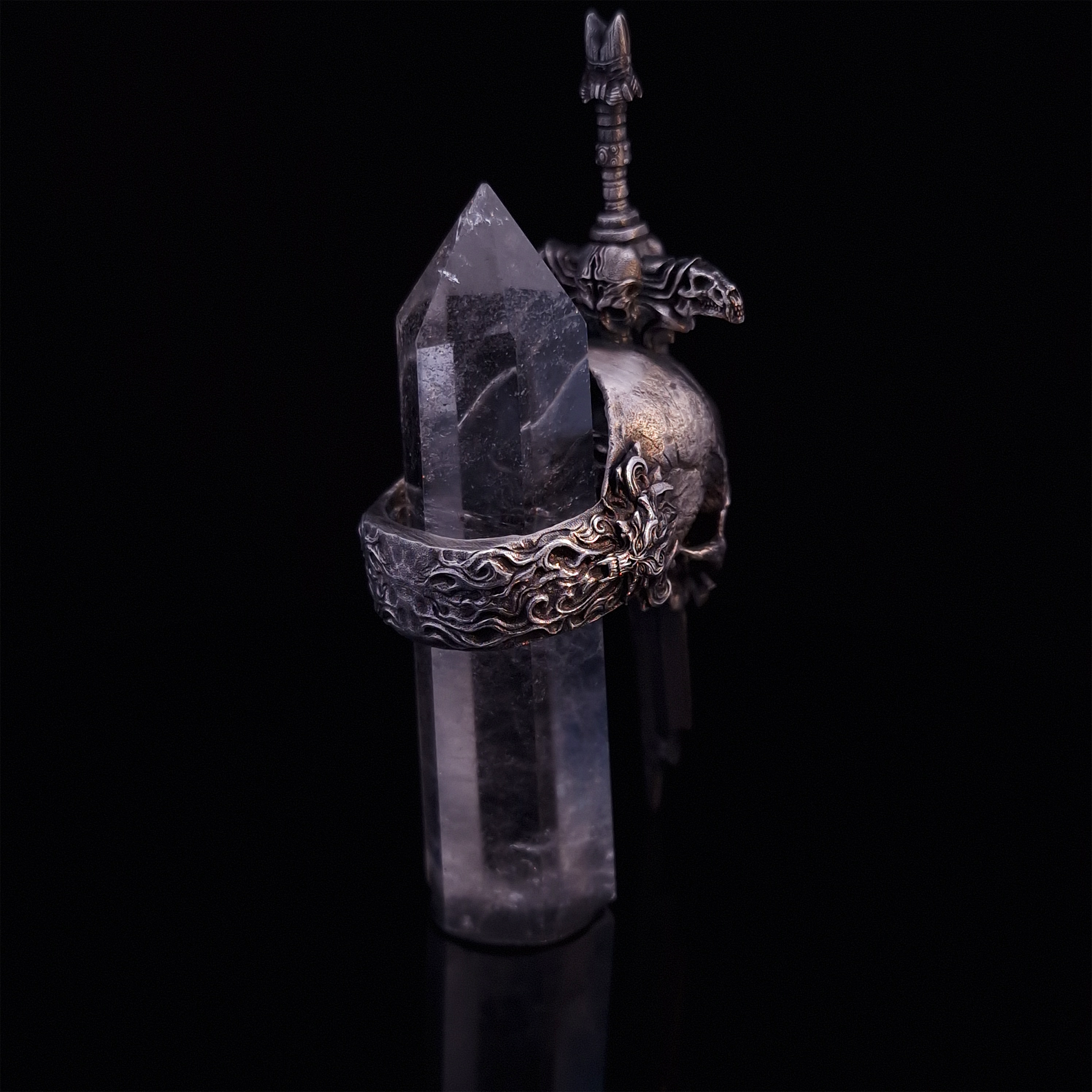 Rear-right view of the Adversarius Mortis ring in the Fallen finish, with crystal support visible, focusing on the intricate band design.