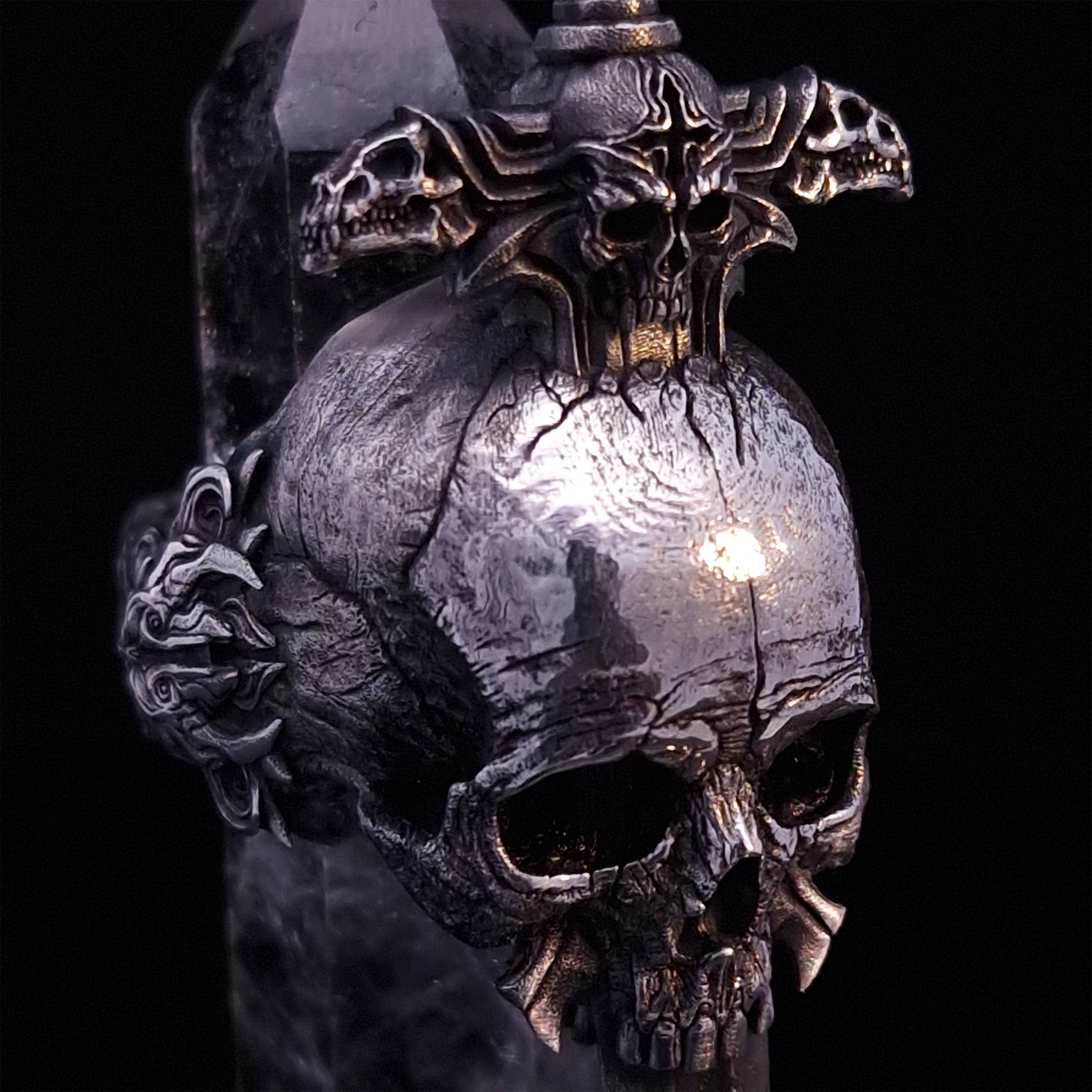 Close-up front-right facing view of the Adversarius Mortis ring in the Fallen finish, supported by a crystal for balance, shown on a turntable with a black background.
