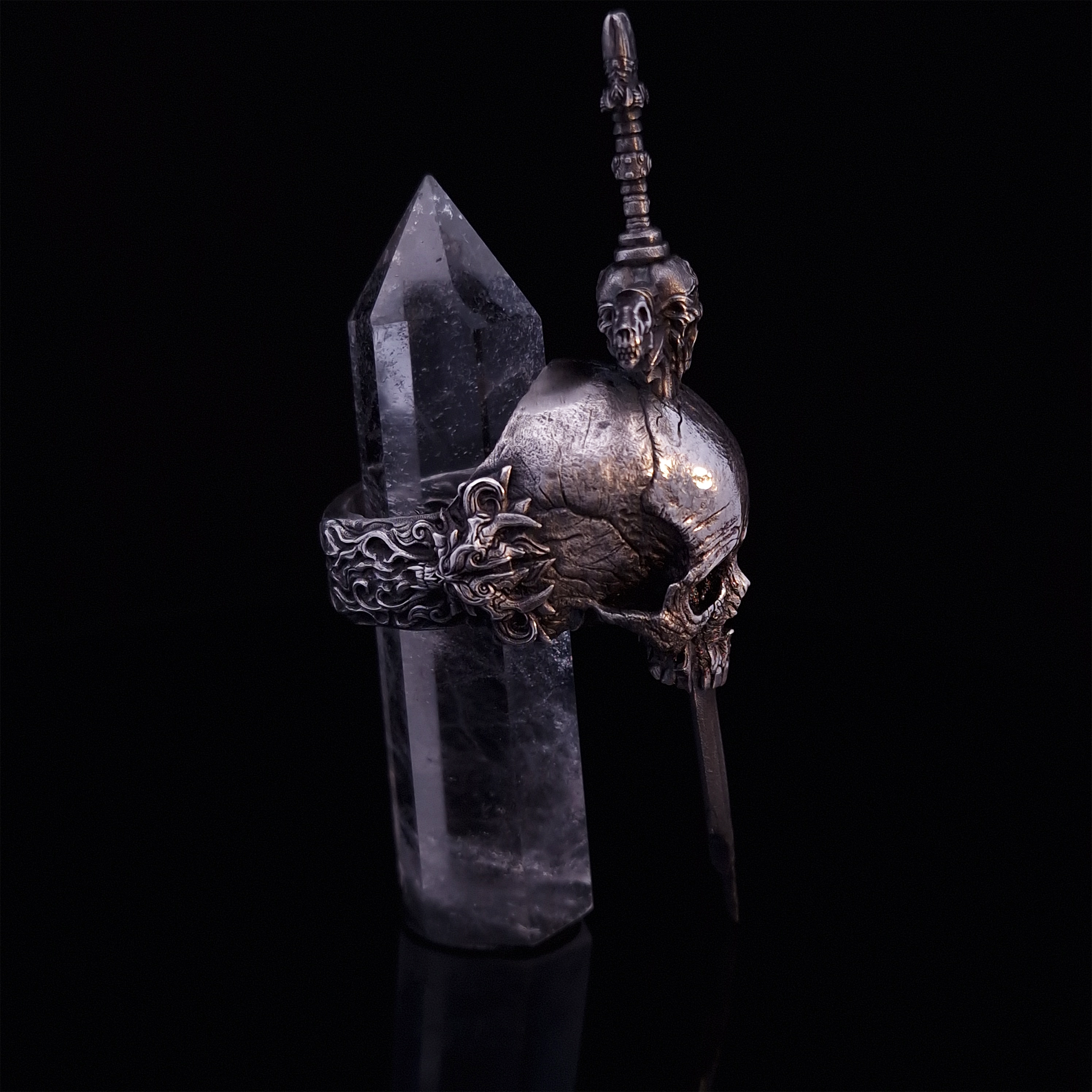 Side-right view of the Adversarius Mortis ring in the Fallen finish, with crystal support visible, highlighting the intricate band design on a turntable.