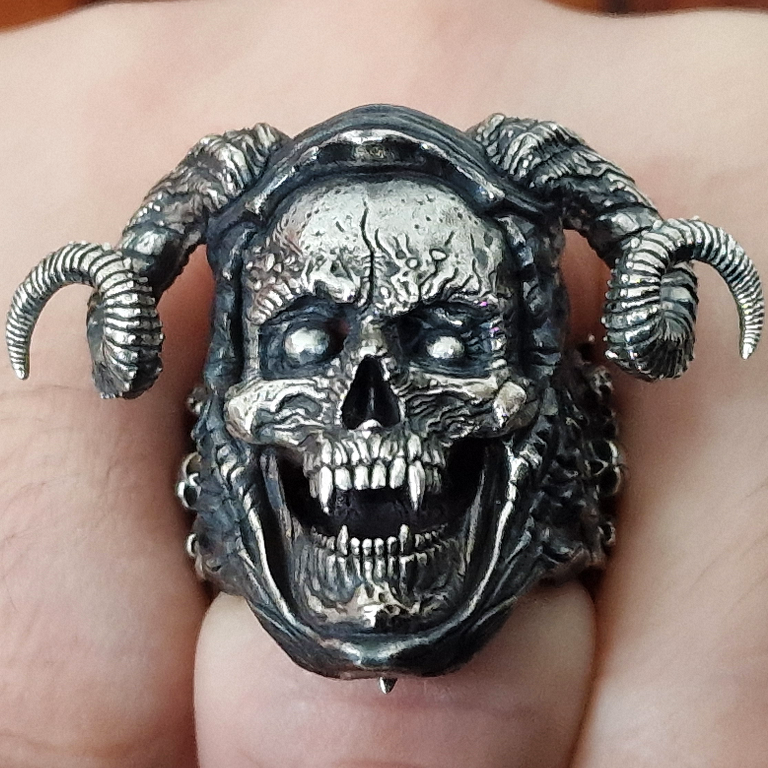 Fist pointed toward the camera in natural light, wearing the Sword of Damocles ring in the Fallen finish.