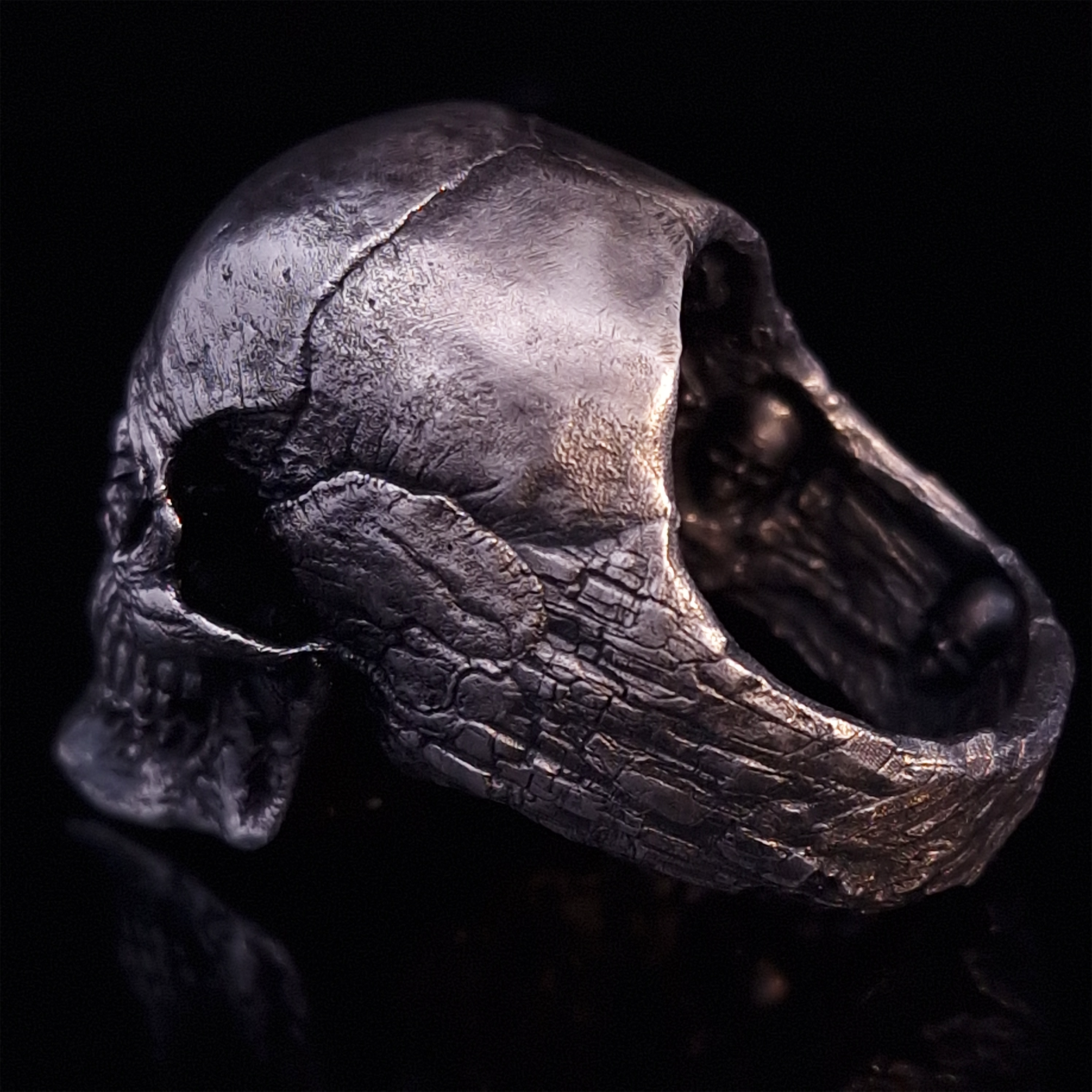 Back-left view of the Invidia Mortis ring in the Fallen finish, on a turntable with a black background.