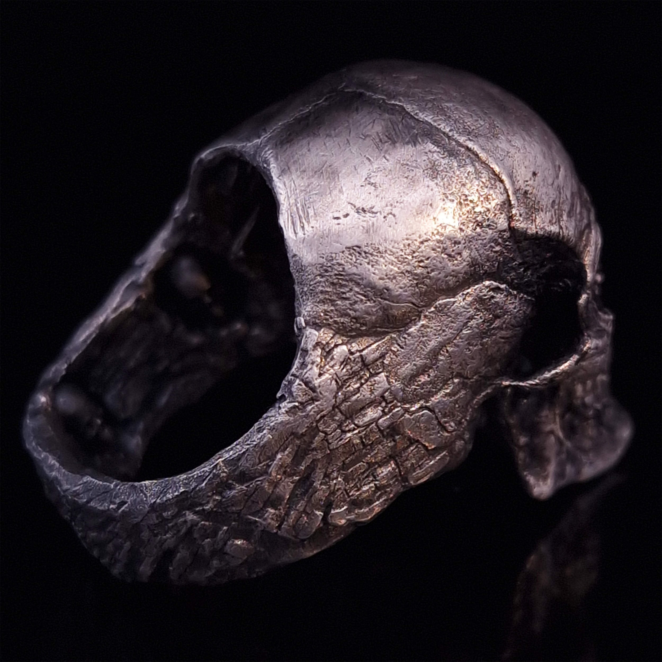 Back-right view of the Invidia Mortis ring in the Fallen finish, on a turntable with a black background.