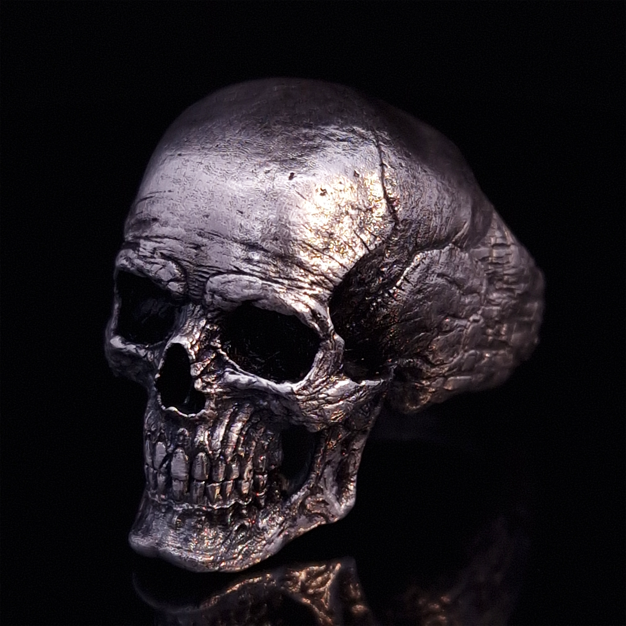 Front left view of the Invidia Mortis ring in the Fallen finish, displayed on a turntable against a black background.