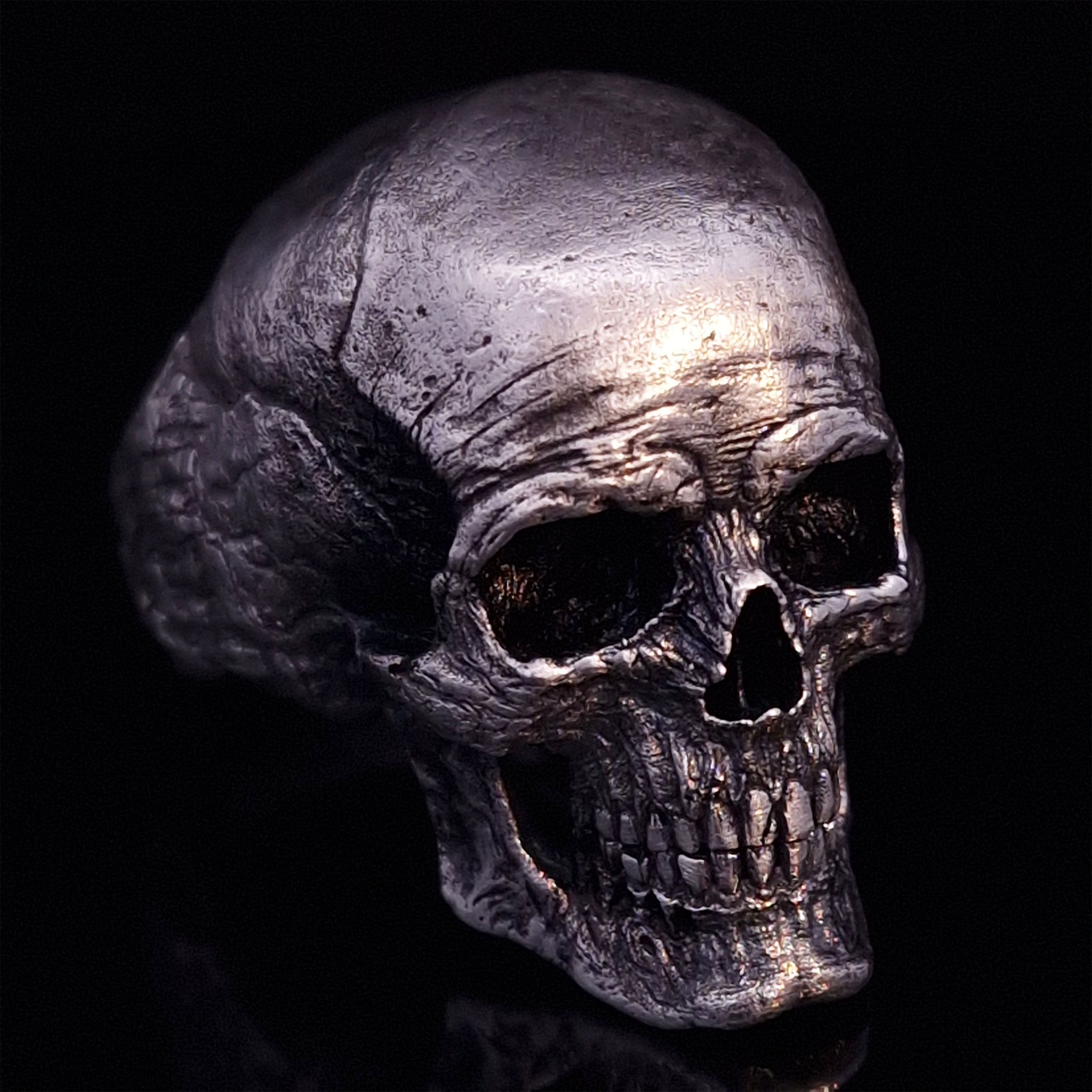 Front right view of the Invidia Mortis ring in the Fallen finish, displayed on a turntable against a black background.