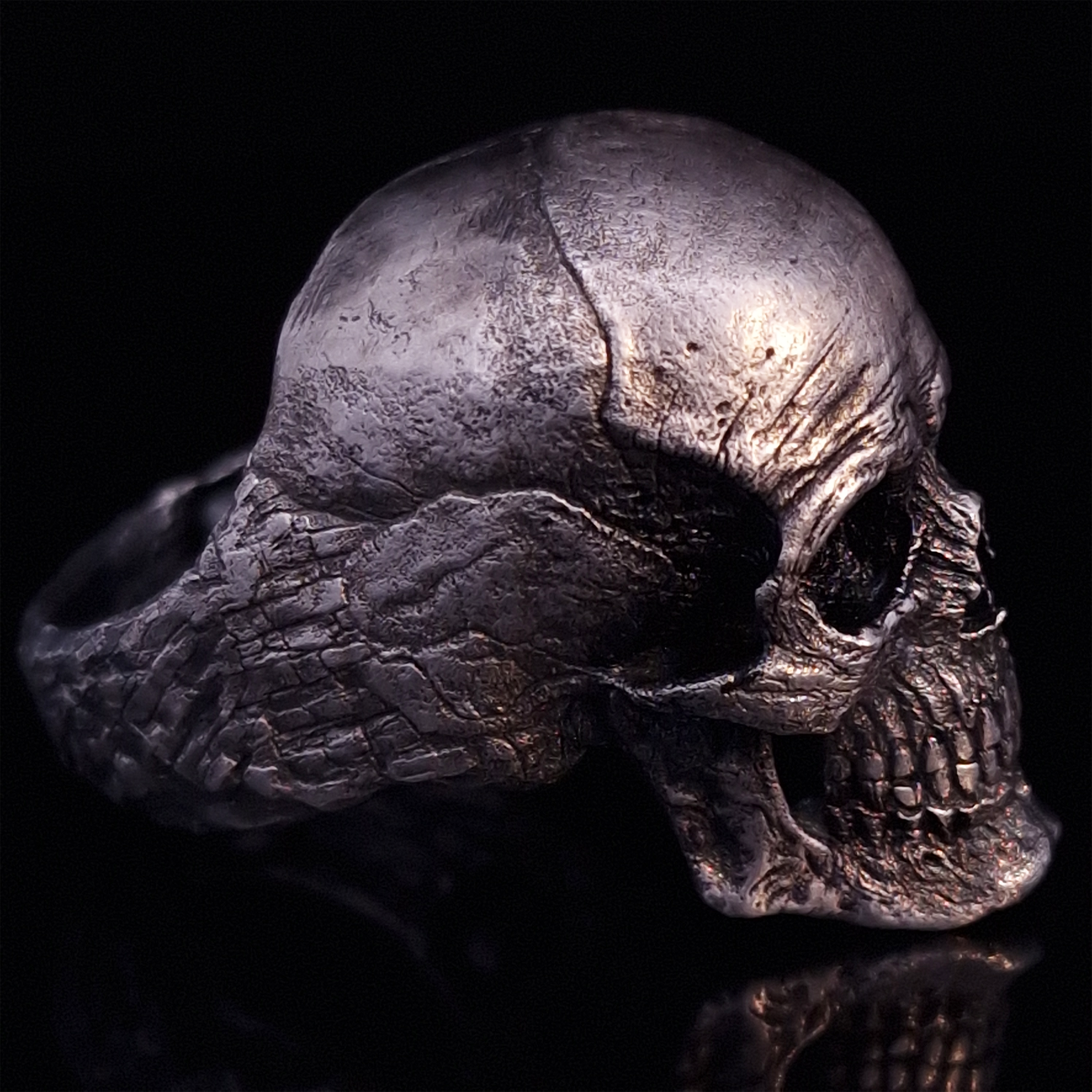 Side-right view highlighting the detailed band of the Invidia Mortis ring in the Fallen finish, shown on a turntable with a black background.