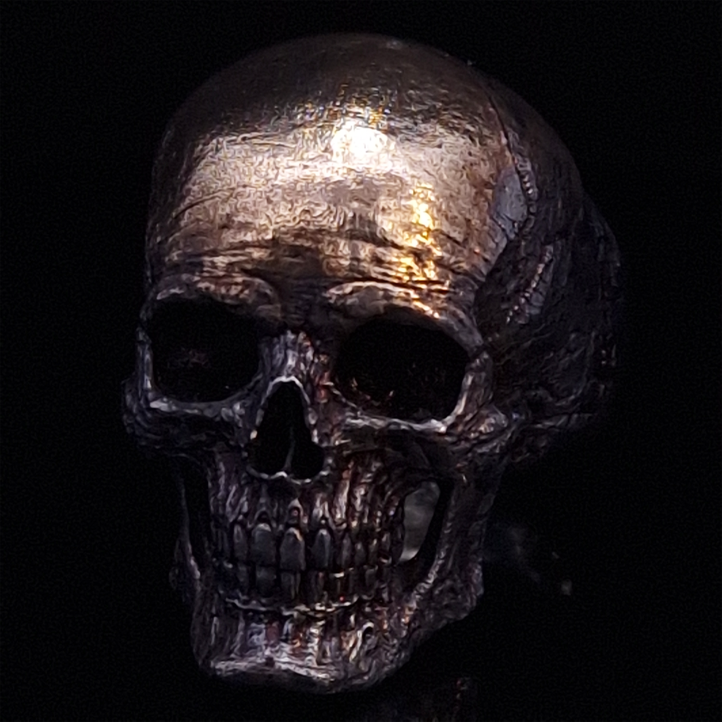 Front diagonal-left view of the Invidia Mortis ring in the Revenant 1 finish, displayed on a turntable against a black background.