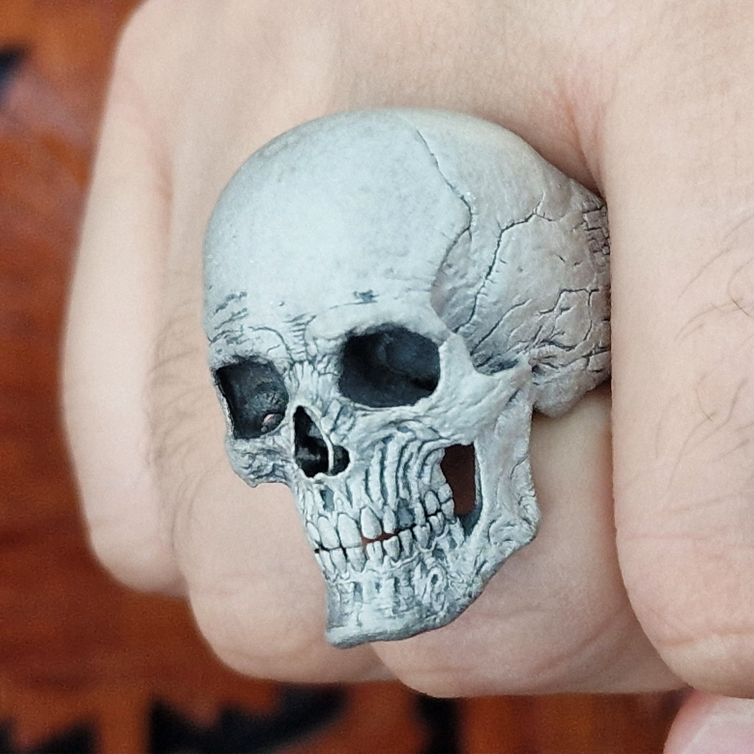 Fist pointed toward the camera in natural light, wearing the Invidia Mortis ring in the Wraith finish, highlighting its details and texture.