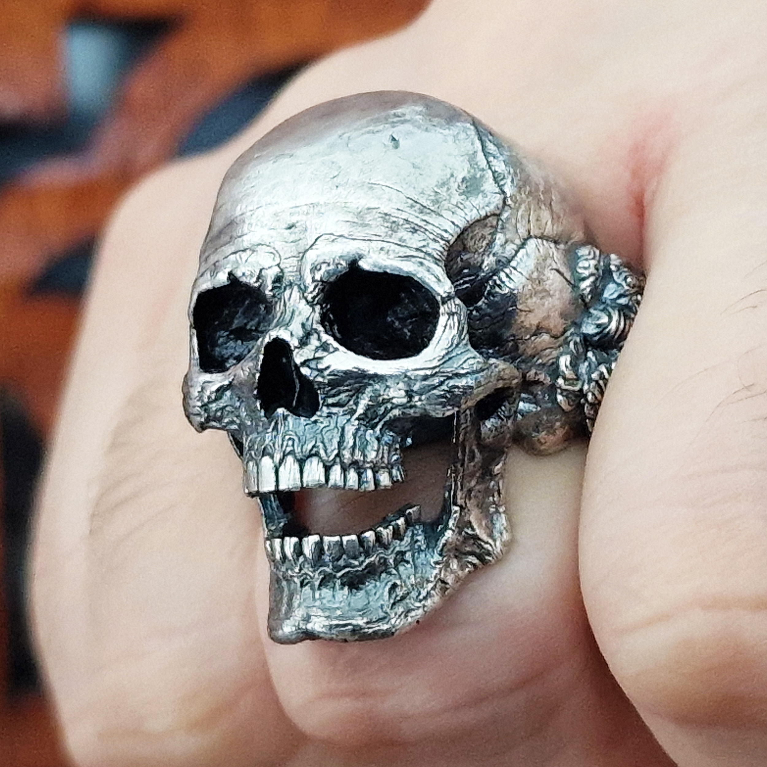 Fist pointed toward the camera in natural light, wearing the Nexus Mortis ring in the Fallen finish, highlighting its details and texture.