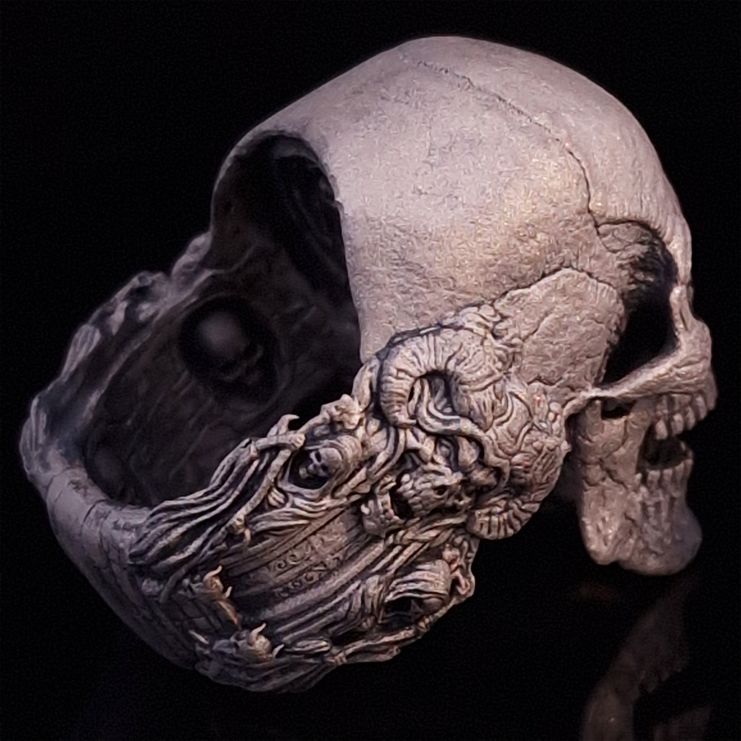 Back-right view of the Nexus Mortis ring in the Wraith finish, focusing on the reaper band, on a turntable with a black background.
