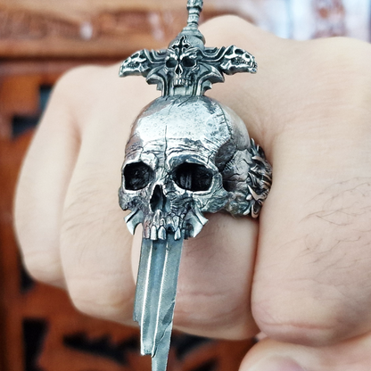 Fist pointed toward the camera in natural light, wearing the Adversarius Mortis ring in the Fallen finish, highlighting its details and texture.