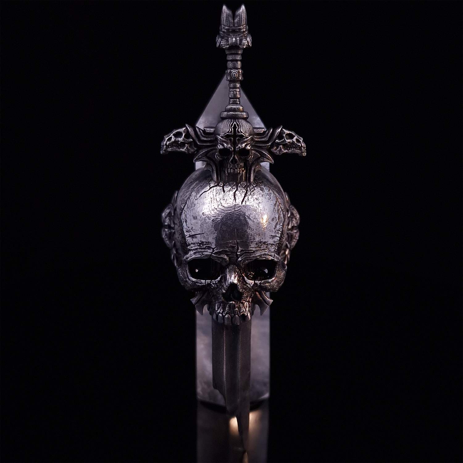 Front-facing view of the Adversarius Mortis ring in the Fallen finish, supported by a crystal for balance, shown on a turntable with a black background.