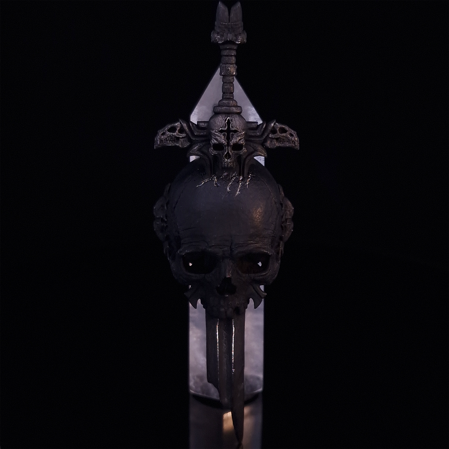 Front-facing view of the Adversarius Mortis ring in the Revenant 2 finish, supported by a crystal for balance, shown on a turntable with a black background.