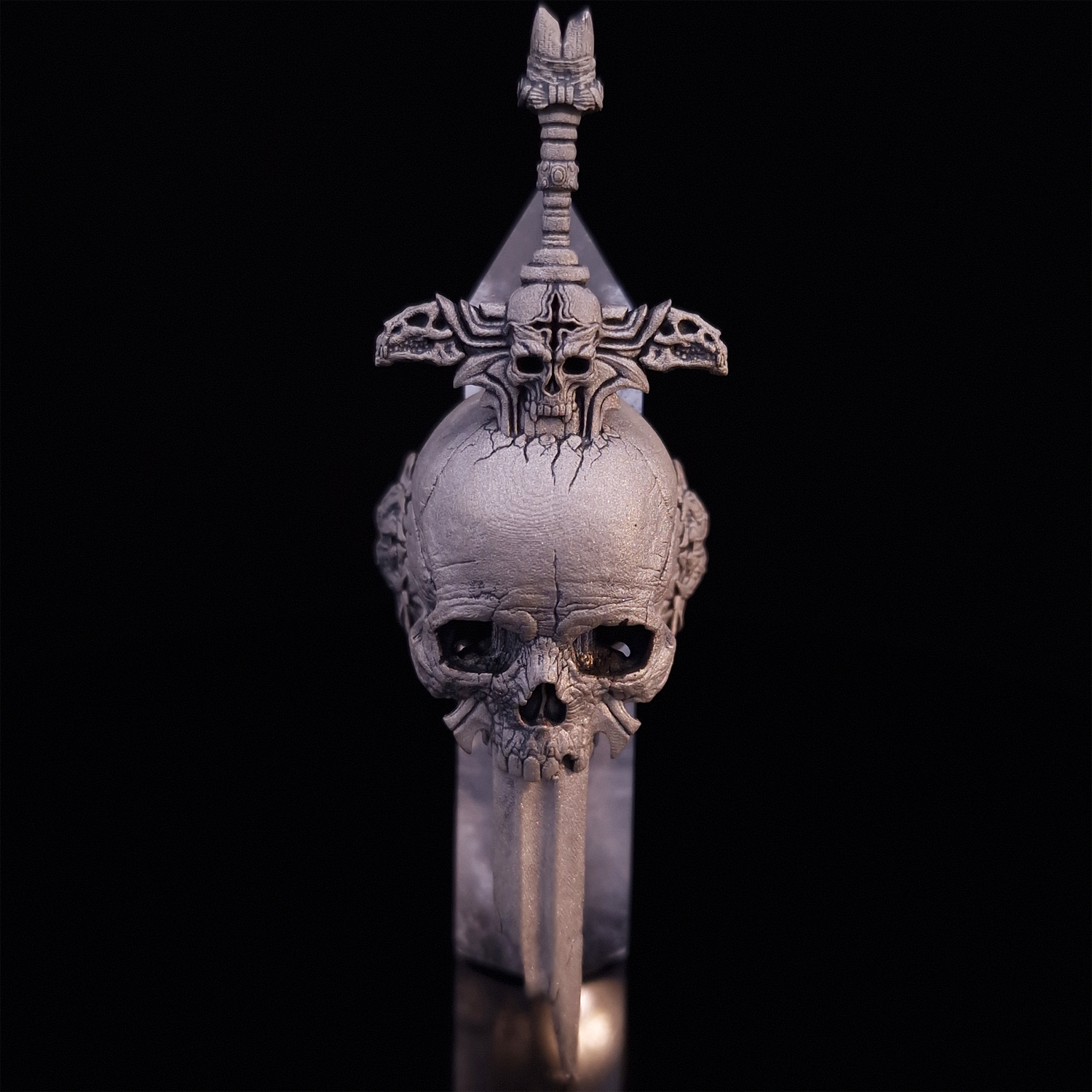 Front-facing view of the Adversarius Mortis ring in the Wraith finish, supported by a crystal for balance, shown on a turntable with a black background.