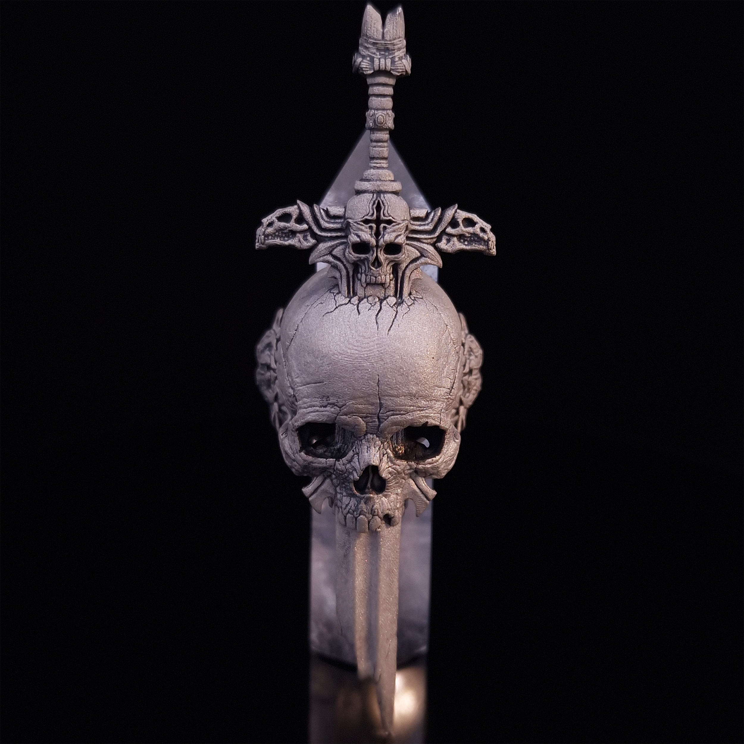 Front-facing view of the Adversarius Mortis ring in the Wraith finish, supported by a crystal for balance, shown on a turntable with a black background.