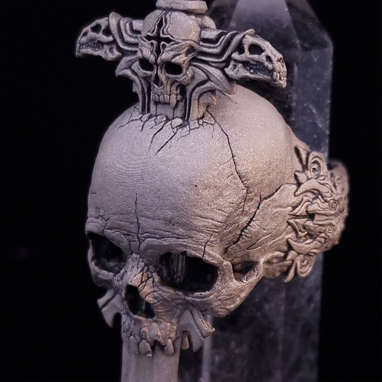 Close-up front-left facing view of the Adversarius Mortis ring in the Wraith finish, supported by a crystal for balance, shown on a turntable with a black background.