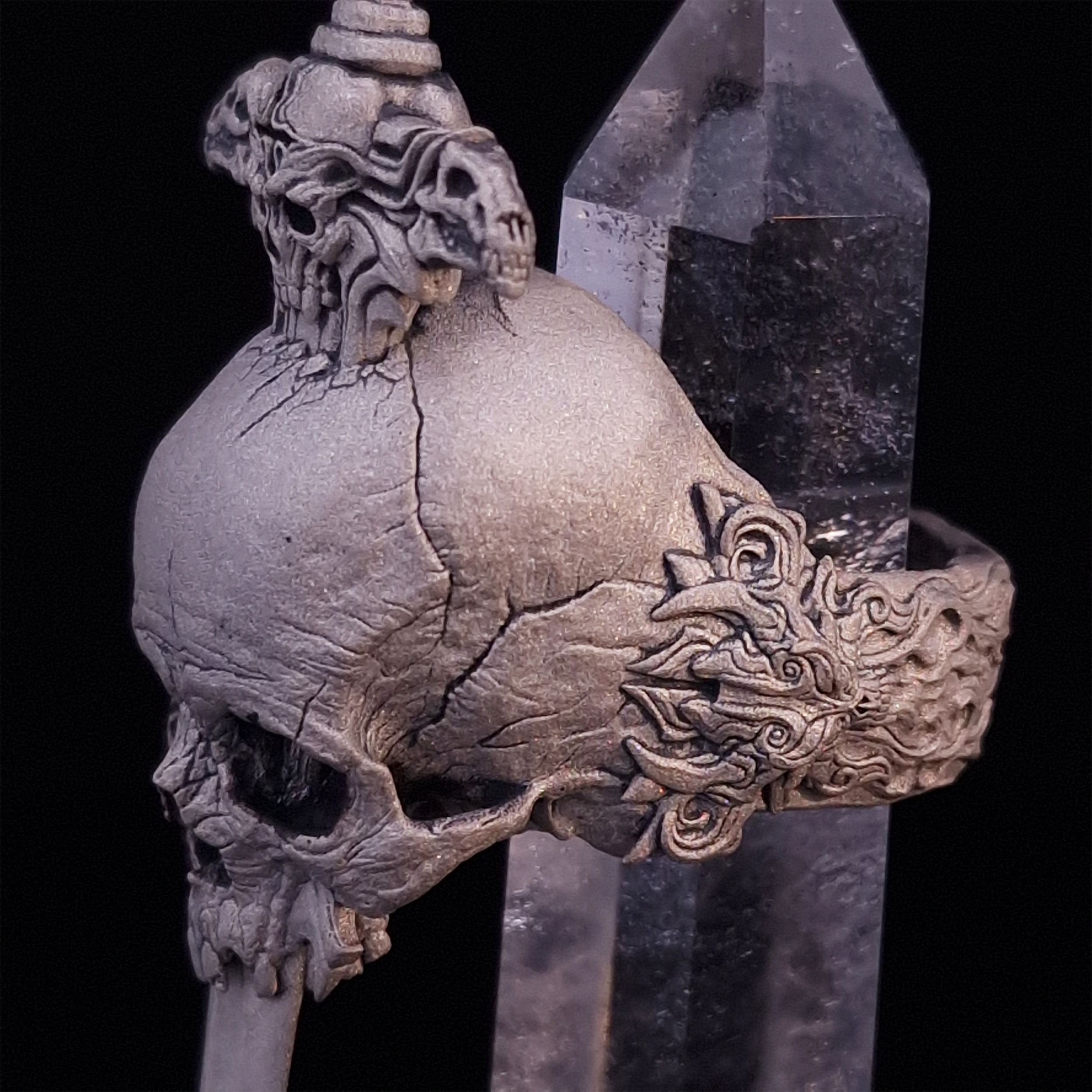 Close-up side-left view of the Adversarius Mortis ring in the Wraith finish, with crystal support visible, highlighting the intricate band design on a turntable.