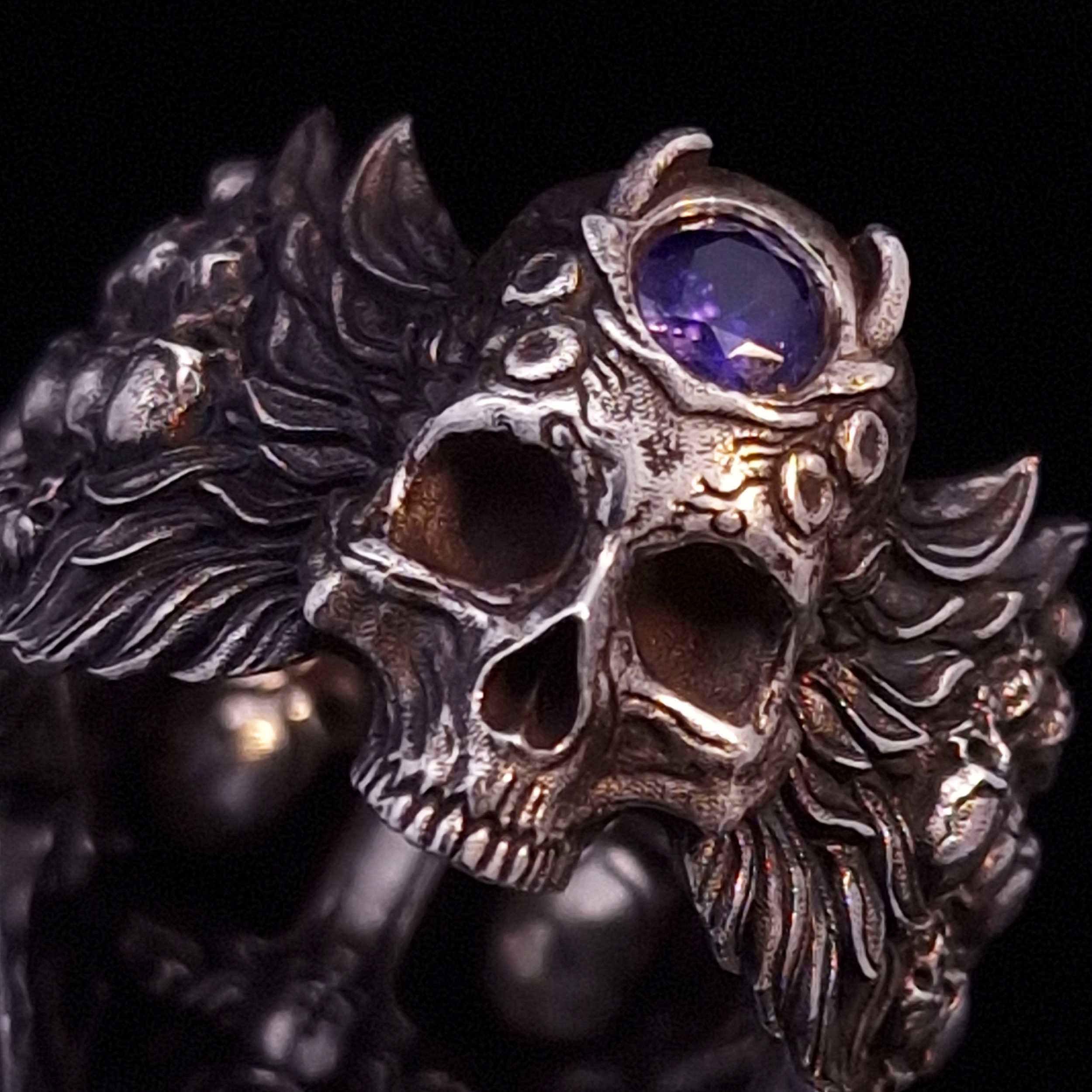Close-up back view of the Sword of Damocles ring in the Fallen finish, focusing on the gemstone detail, on a turntable with a black background.