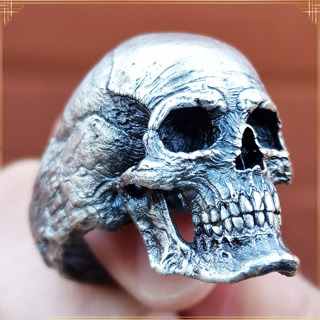 Handheld image of the Invidia Mortis ring in the Fallen finish, with sunlight revealing the oxidized detailing and antique tones