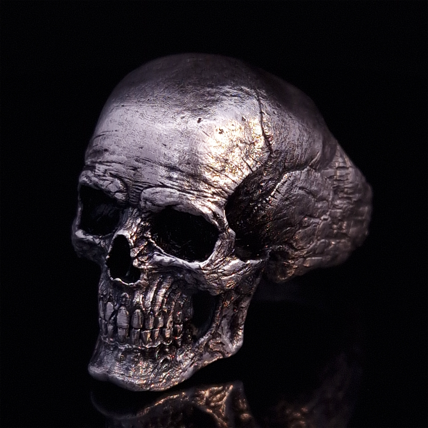 Front left view of the Invidia Mortis ring in the Fallen finish, displayed on a turntable against a black background.