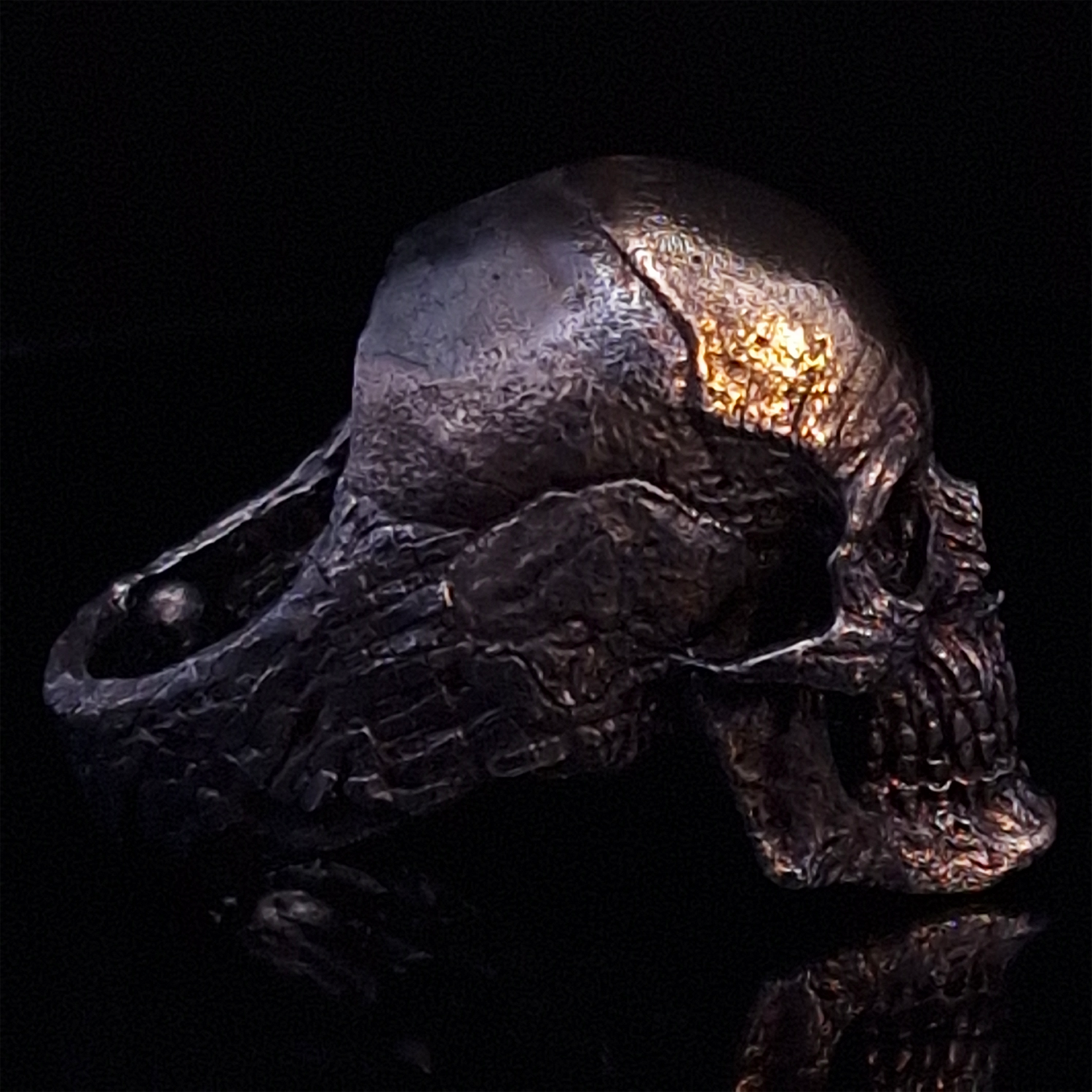 Side-right view highlighting the detailed band of the Invidia Mortis ring in the Revenant 1 finish, shown on a turntable with a black background.