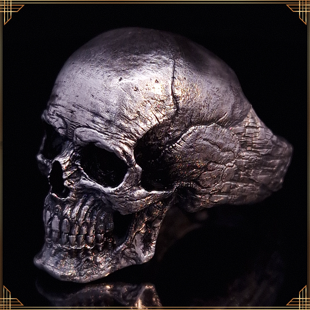 Close-up of the Invidia Mortis ring in the Fallen finish, shown facing the left, against a black background with a gold border.