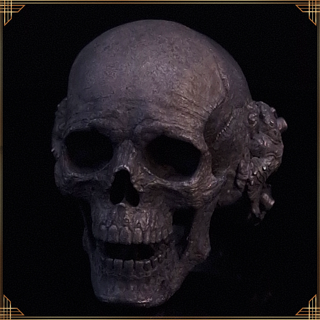 Close-up of the Nexus Mortis ring in the Revenant 3 finish, shown facing slightly to the left, against a black background with a gold border.